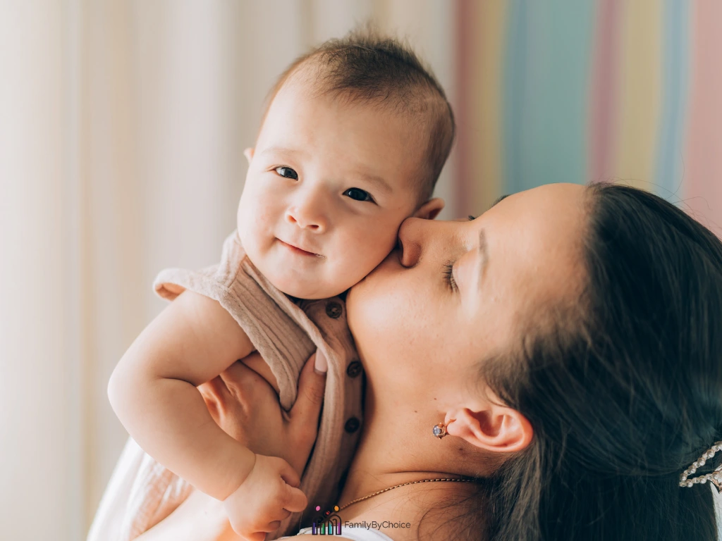 mom holding and kissing a baby